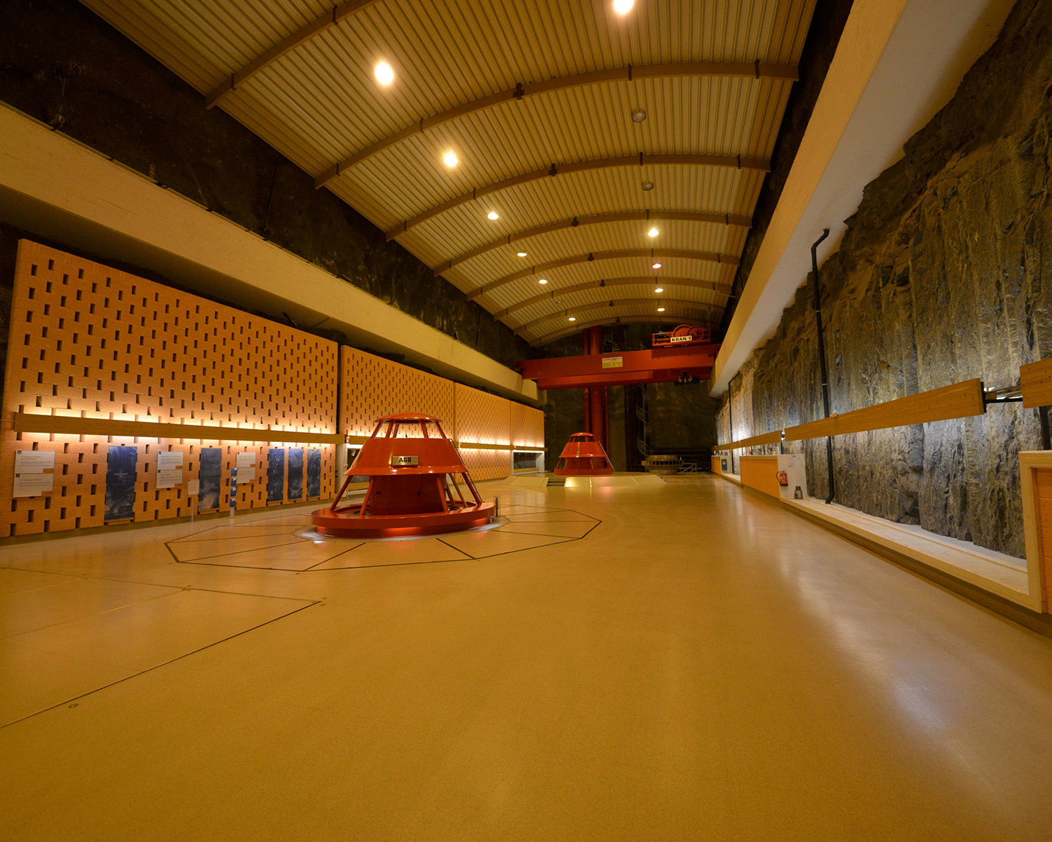 Maskinsalen med aggregater, lys og råsprengt fjellvegg.