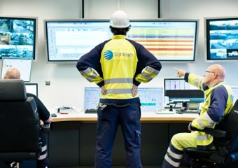 Tre arbeidere med ryggen til på kontrollrommet
