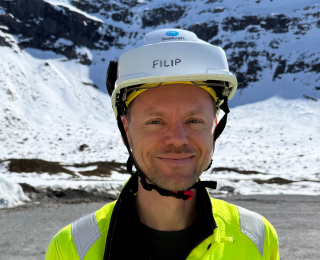 Mann i blå skjorte ser inn i kameraet
