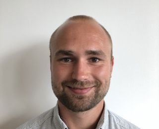 Mann i hvit skjorte smiler til kameraet
