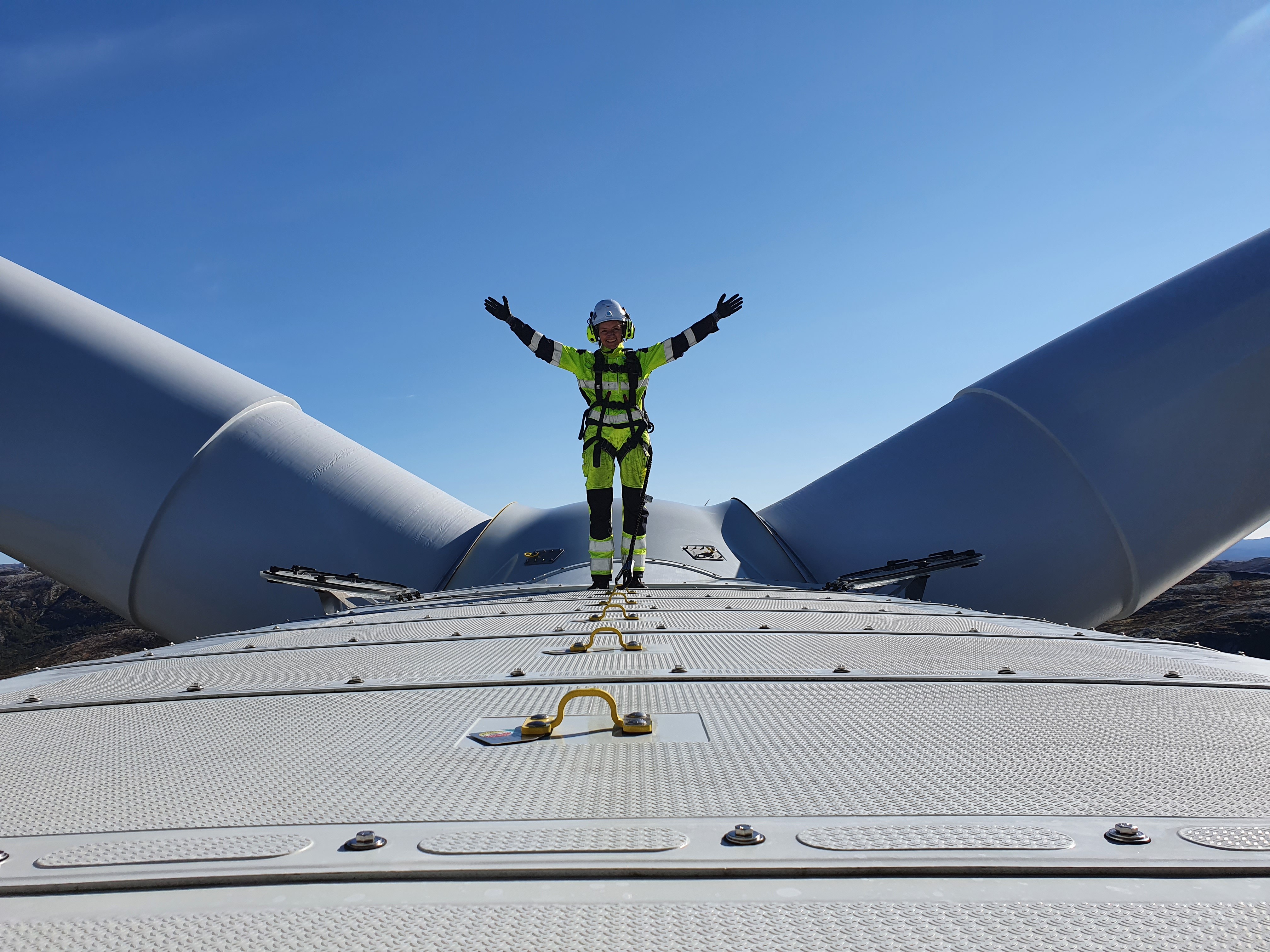 Dame står på toppen av en vindturbin
