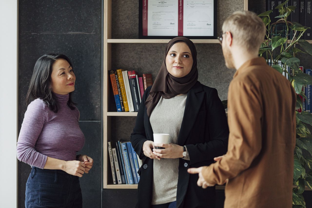 Tre ansatte i i kontorlanskap snakker