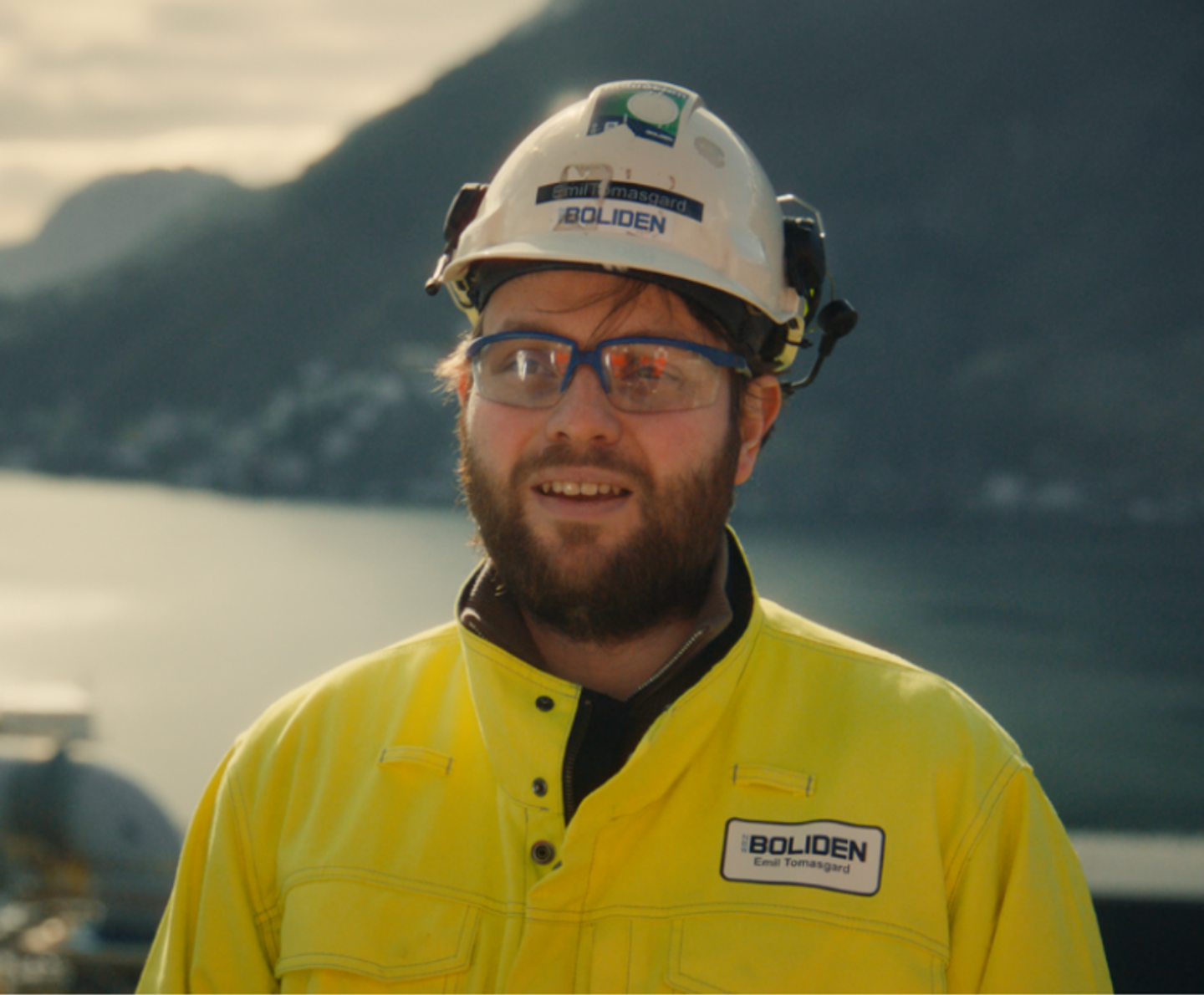 Mann i verneutstyr med vann og fjell i bakgrunnen