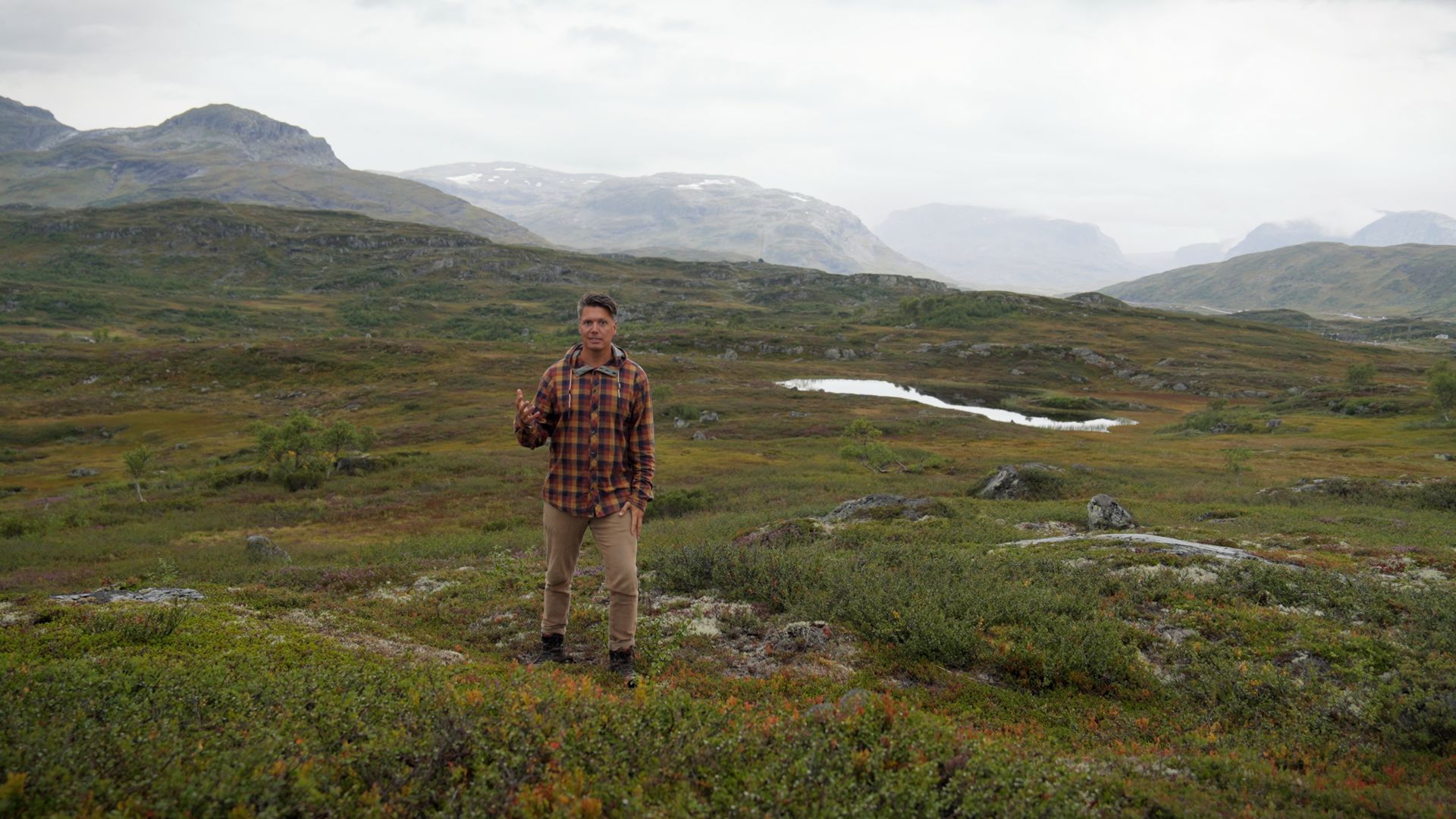 Andreas Wahl snakker til kameraet i grønt fjellandskap