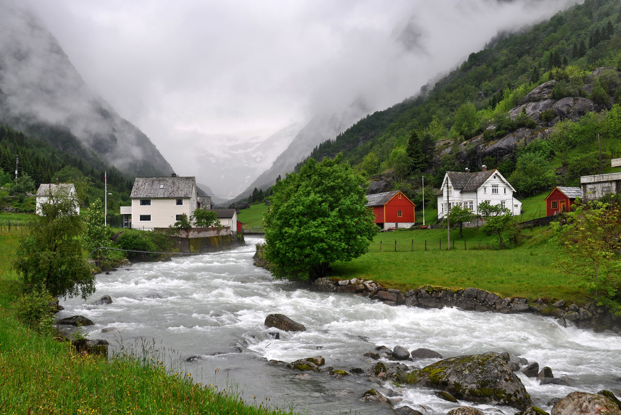 Hus langs en elv i regnvær
