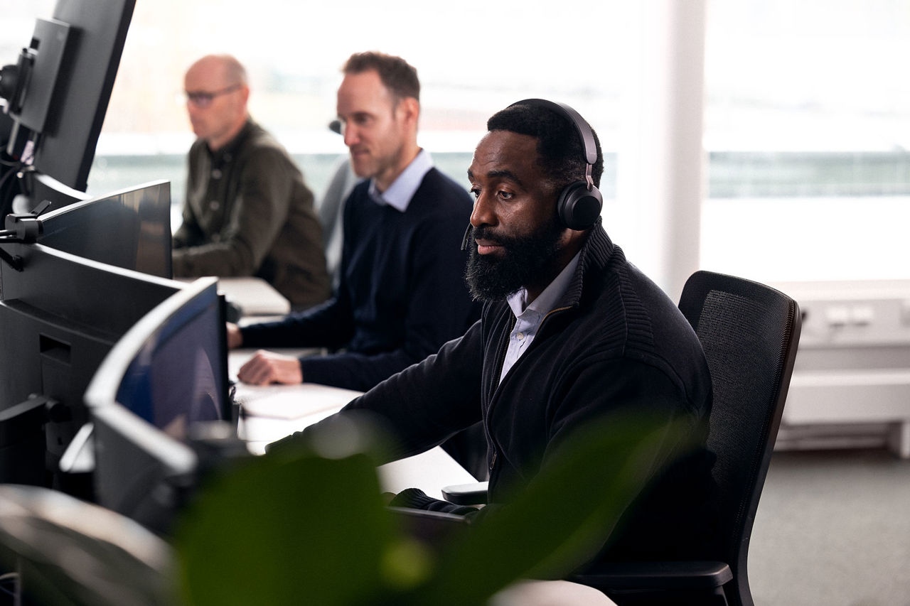 Mann med headset ser på en skjerm